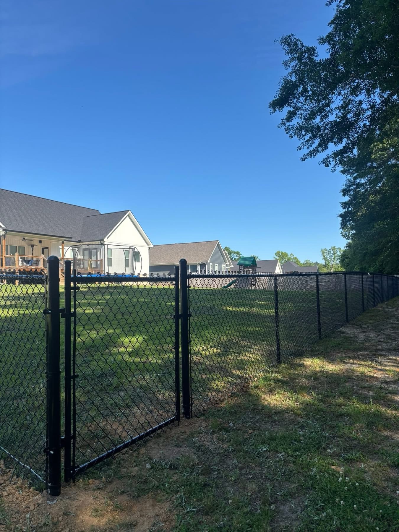 Black chain link fence by white farmhouse
