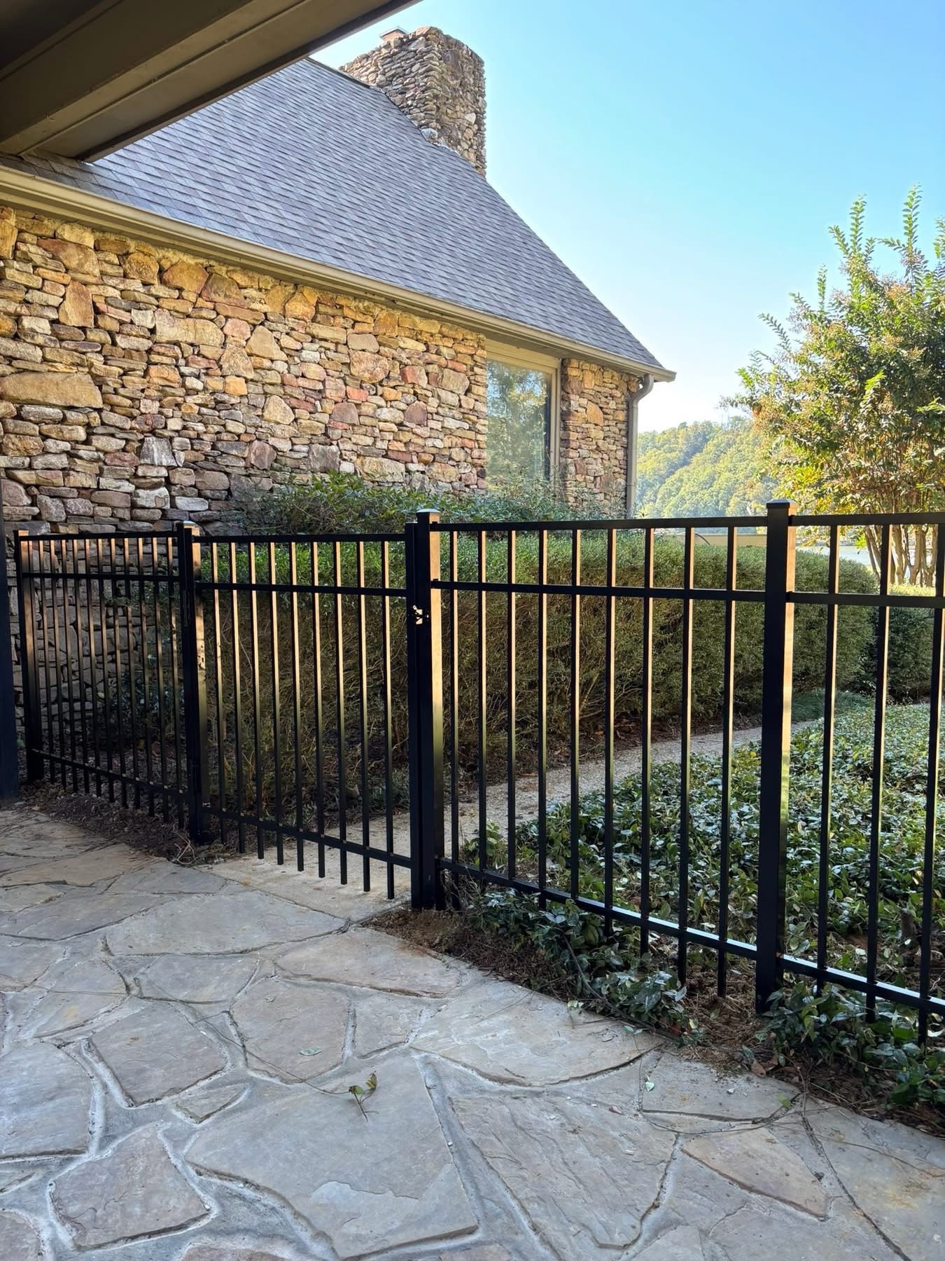 Black ornamental aluminum fence along brick home