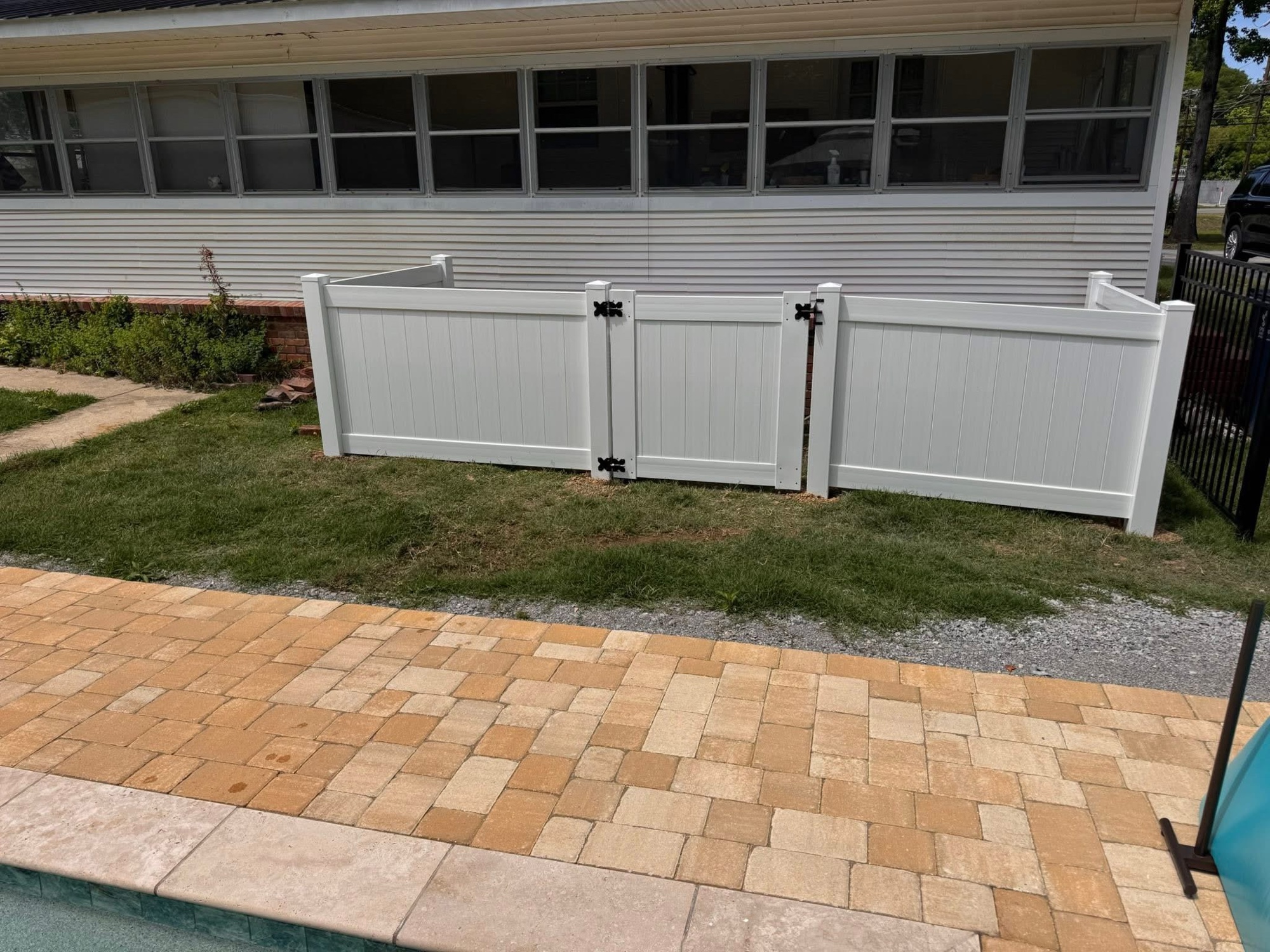 White vinyl fence around pool with paver patio